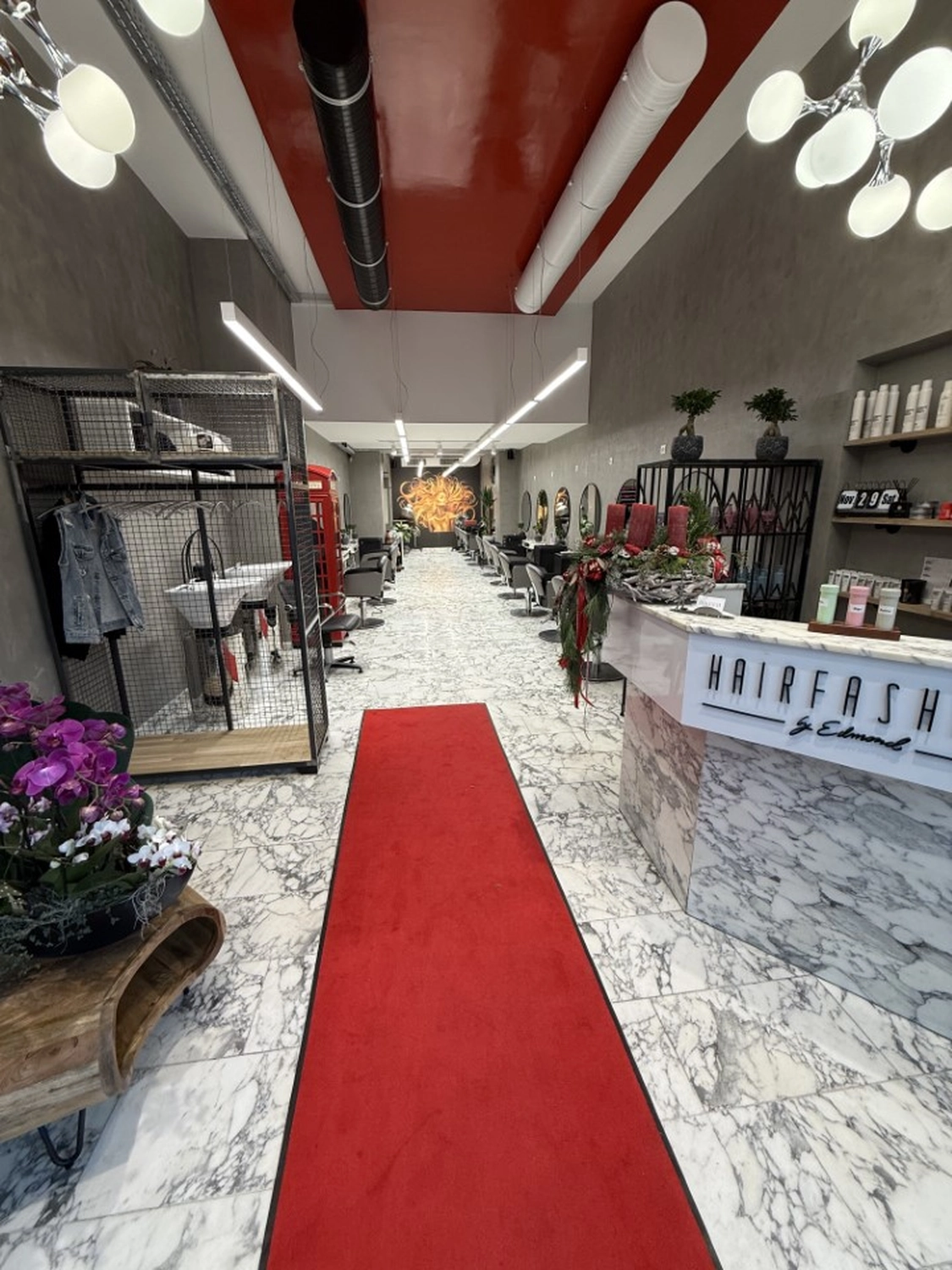 Hairfashion by Edmond - Haarschnitt und Styling - Innenansicht eines Friseursalons mit einer roten Telefonzelle.