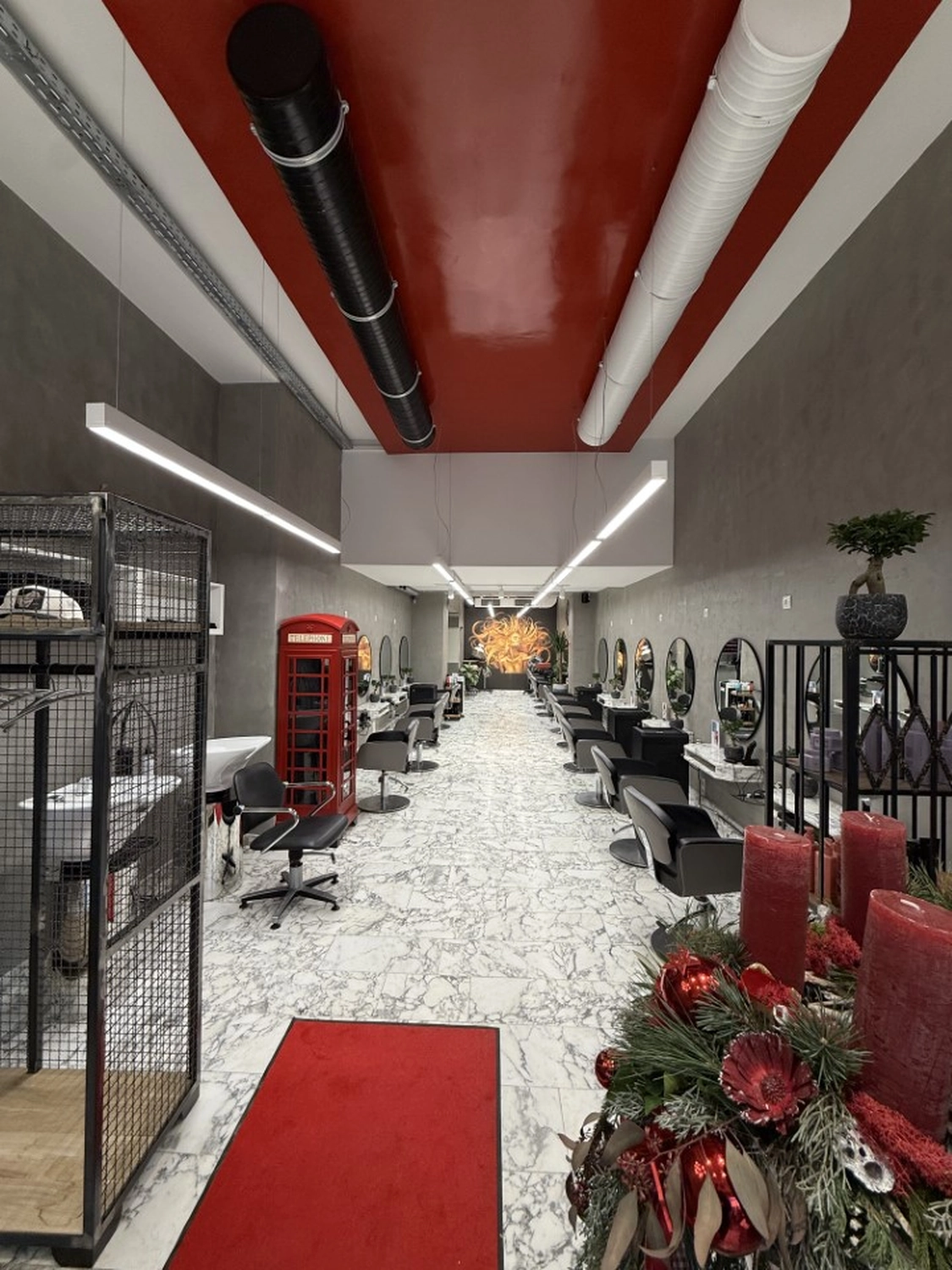 Hairfashion by Edmond - Haarschnitt und Styling - Innenansicht eines Friseursalons mit einer roten Telefonzelle.