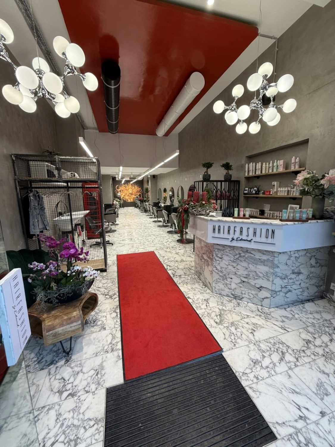 Hairfashion by Edmond - Haarschnitt und Styling - Innenansicht eines Friseursalons mit einer roten Telefonzelle.