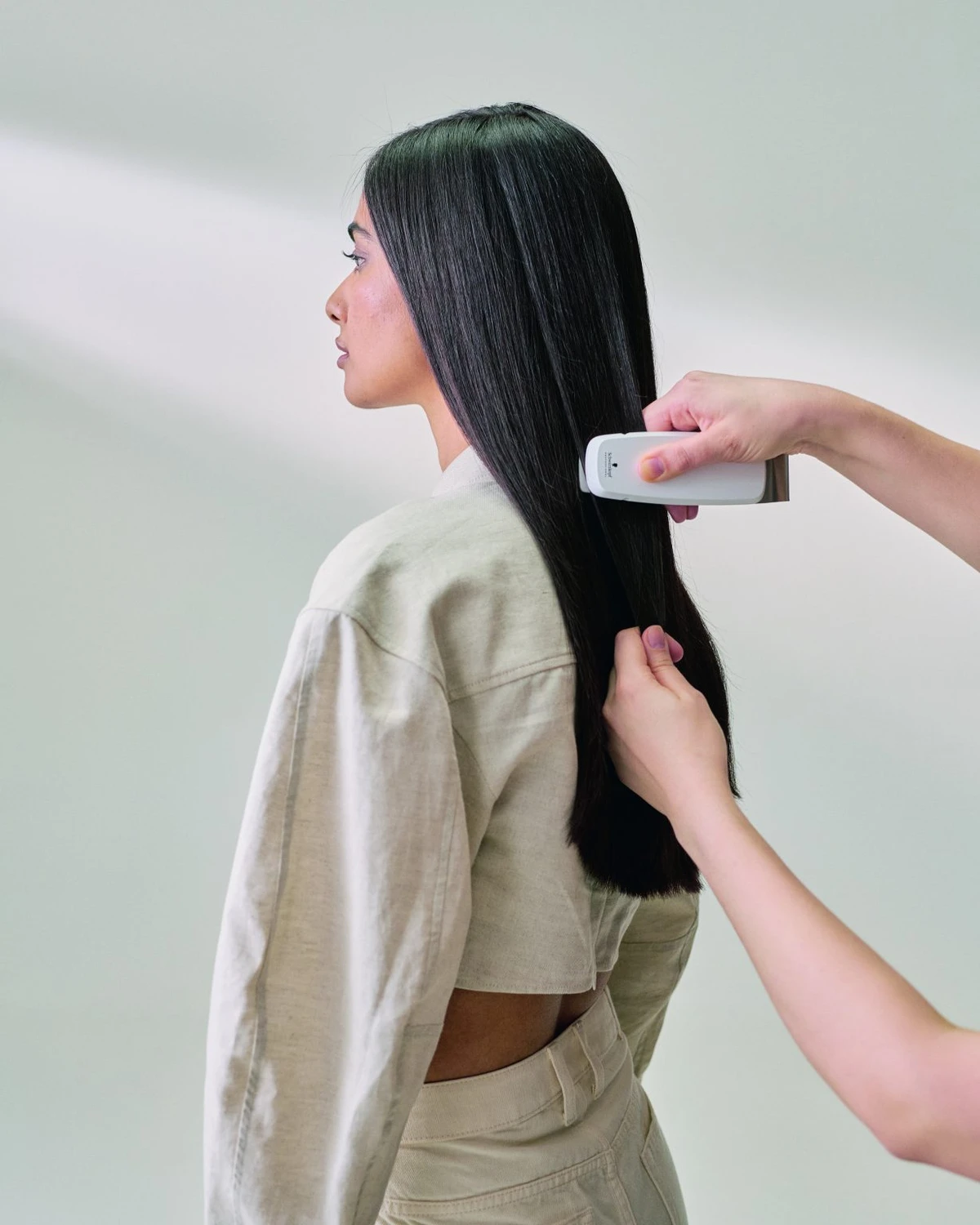 Hairfashion by Edmond - Haarschnitt und Styling - Das Gerät wird an den langen, dunklen Haaren einer Person angewendet.