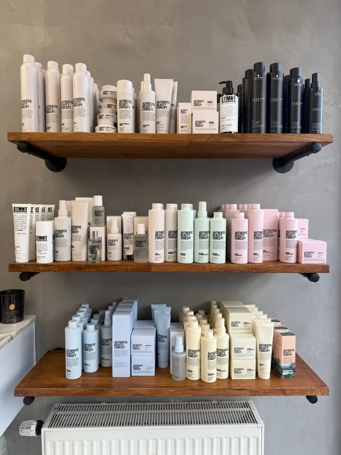 Hairfashion by Edmond - Haarschnitt und Styling - Regale mit verschiedenen weißen, schwarzen, hellgrünen und rosafarbenen Flaschen und Schachteln der Haarpflegeprodukte von Authentic Beauty Concept.