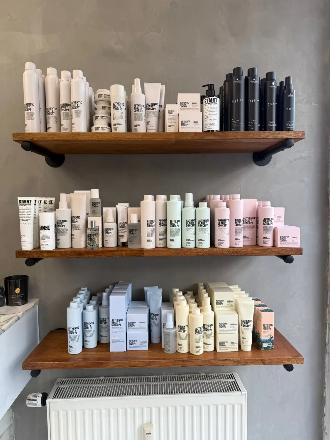 Hairfashion by Edmond - Haarschnitt und Styling - Regale mit verschiedenen weißen, schwarzen, hellgrünen und rosafarbenen Flaschen und Schachteln der Haarpflegeprodukte von Authentic Beauty Concept.