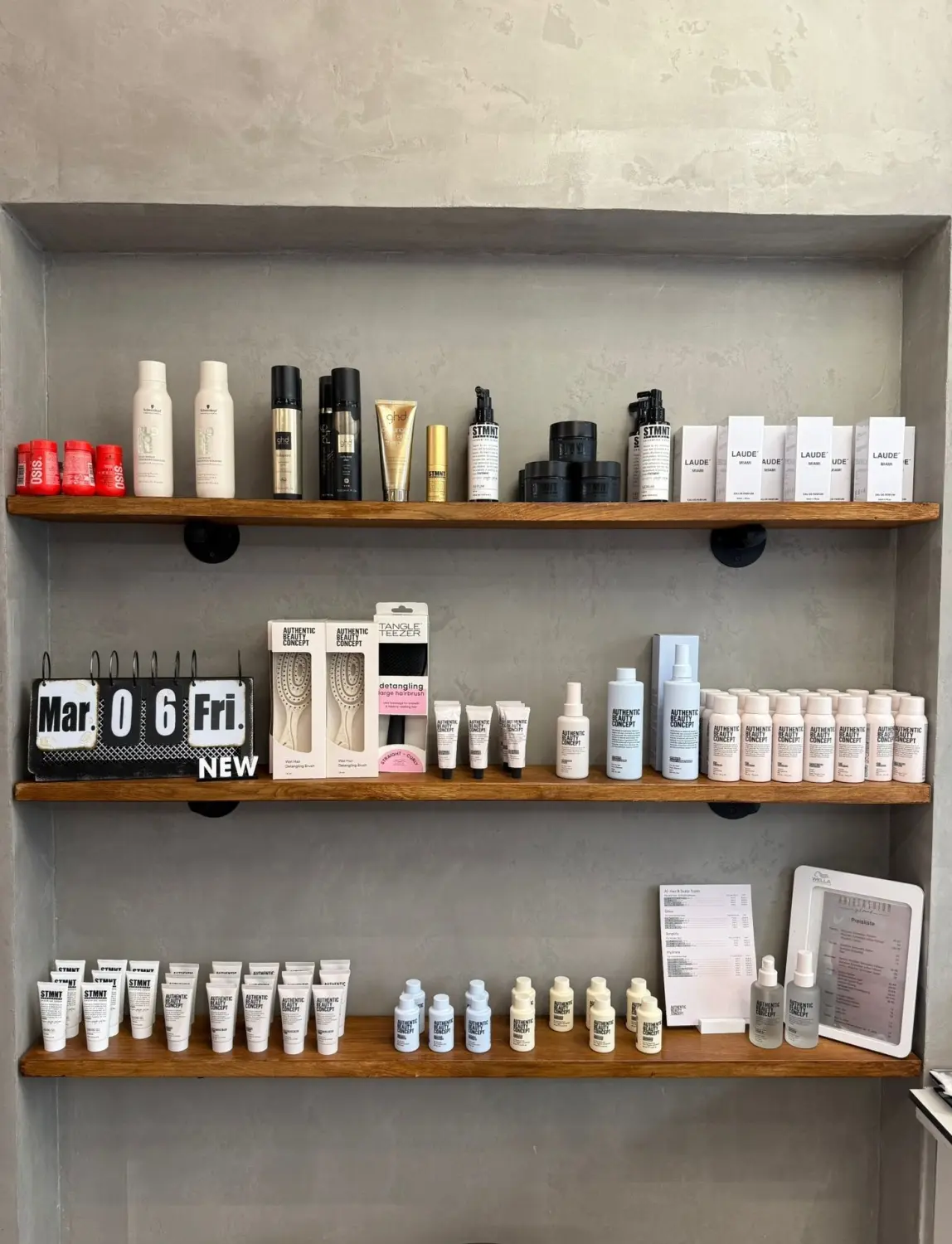 Hairfashion by Edmond - Haarschnitt und Styling - Regale mit verschiedenen weißen, schwarzen, hellgrünen und rosafarbenen Flaschen und Schachteln der Haarpflegeprodukte von Authentic Beauty Concept.